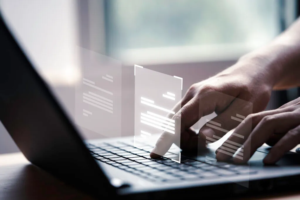 A close-up of a person's hands using a laptop keyboard with a digital overlay of document icons, representing a Data Protection Officer utilizing compliance automation software to manage digital records and DPDP Act requirements